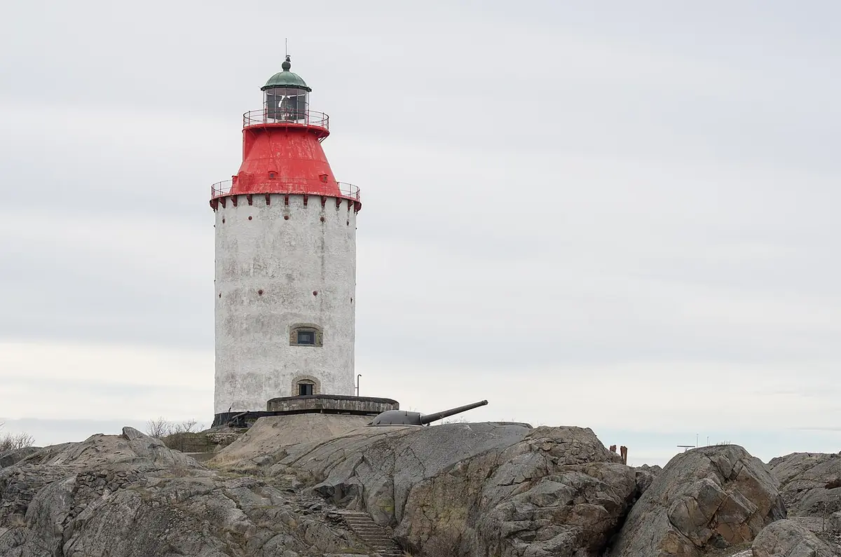 Image A: A white lighthouse with a red lantern room on bare rocks under a gray sky